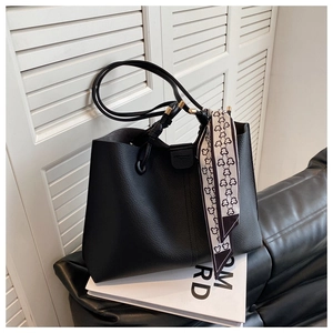 Detail view of black pebble leather tote bag with a bear pattern scarf on the handle