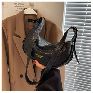 Detail of black pebbled leather crescent bag with gold buckle and fashion text logo