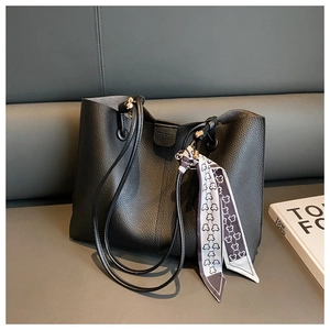 Detail of black pebbled leather tote bag with printed silk scarf on the handle strap