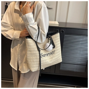 Detail of straw tote bag with black Summer embroidery and plush pearl charm