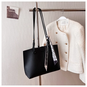 Detail of black pebbled leather tote bag with elegant floral scarf on the shoulder strap