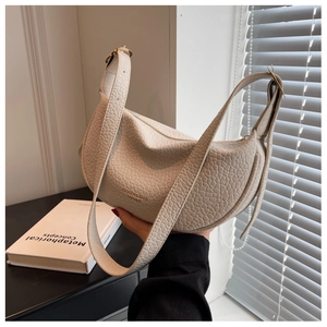 Detailed macro view of cream crocodile embossed leather and wide strap on crescent bag