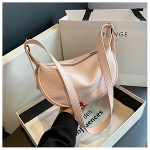Detail of light pink lychee leather half-moon bag with gold logo and wide shoulder strap