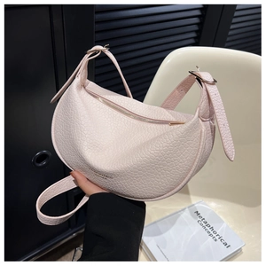 Detailed shot of the pebbled leather texture and gold zipper on a pink crescent bag