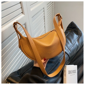 Close-up of amber yellow leather hobo bag with stone texture and wide shoulder strap
