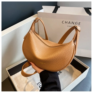 Close-up of warm camel pebbled leather shoulder bag with adjustable strap and zip closure