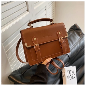 Primer plano de bolso vintage marrón en cuero PU con hebillas y asa de mano superior