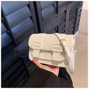 Close-up of white lychee pattern leather bag with gold hardware in classic satchel style