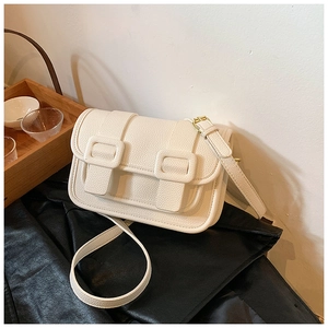 Detail of white cross-body bag with textured leather grain and gold hardware
