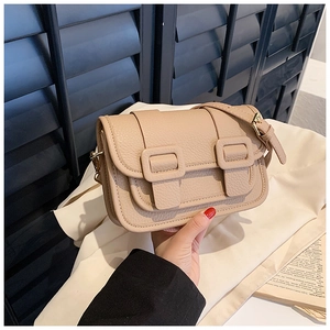 Detail of beige crossbody bag with lychee grain texture and gold hardware accents