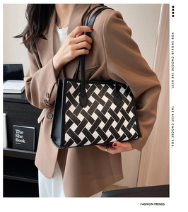 Detailed view of the woven black and white tote bag with long leather shoulder straps