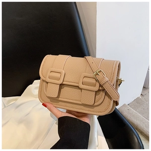 Detailed view of beige pebble grain leather crossbody bag with gold-tone hardware