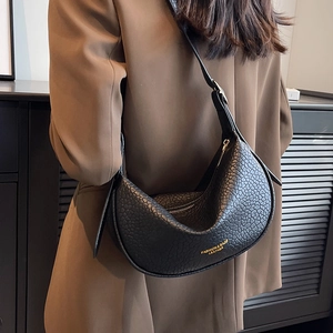 Black pebbled leather half-moon shoulder bag with gold text and zipper on model