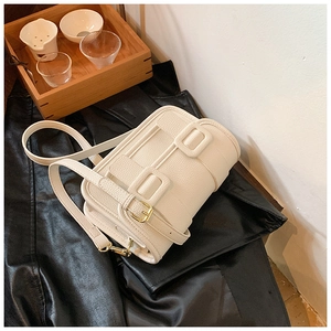 Detail of cream white leather crossbody bag with lychee texture and gold hardware