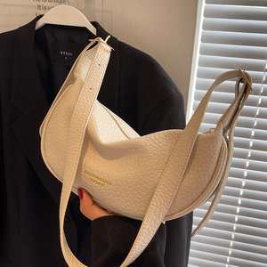 White textured hobo bag with gold lettering shown on a black suit background