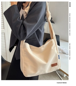 Detail of cream canvas tote bag featuring knotted strap and leather logo patch