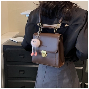 Nahaufnahme brauner Vintage-Lederrucksack mit Goldschnalle und Plüschmonster-Anhänger