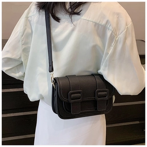 Close-up of black lychee grain crossbody bag with double buckle details on model