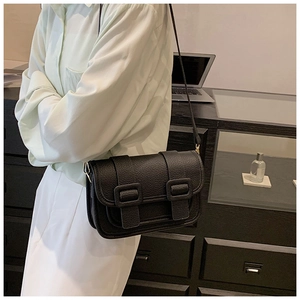 Close-up of black lychee leather crossbody bag with double-buckle flap and vintage strap