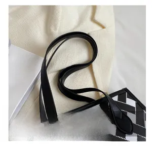 Detail of the leather handle and black and white checkerboard canvas on a tote bag
