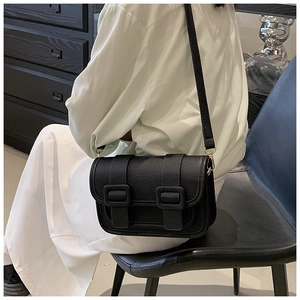 Side view of model wearing a black lychee texture crossbody bag with double straps