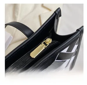 Detail of high-quality smooth gold zipper on black and white geometric tote bag