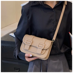 Detail of beige crossbody bag with lychee texture and golden metal buckle accents