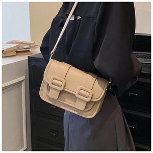 Detail of beige lychee pattern crossbody bag with double square buckles on model