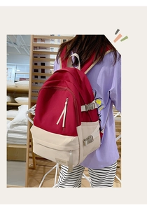 Détail du sac à dos en nylon rouge et crème avec zip frontal et boucle latérale ajustable