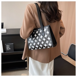 Detail of a large woven tote bag with black and white texture and slim leather straps