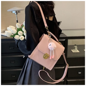 Nahaufnahme der rosa quadratischen Handtasche mit Goldverschluss und Plüschball-Anhänger