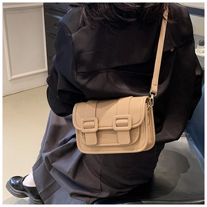 Detail of elegant beige crossbody bag showing lychee grain leather texture and buckles
