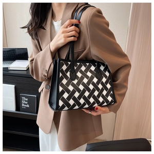 Detail of large tote bag with black and white woven pattern and leather straps