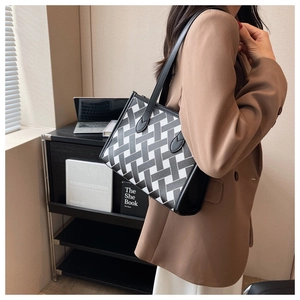 Detailed view of the woven geometric pattern and black leather trim on the tote bag