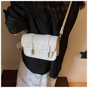 Detailed view of white litchi pattern leather on a crossbody bag with gold hardware