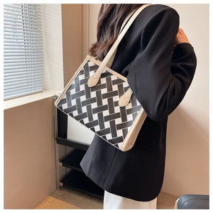 Detail of a black and white geometric woven tote bag with cream leather straps and trim