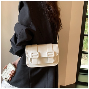 Close-up of white crossbody bag with lychee leather texture and double buckle detail