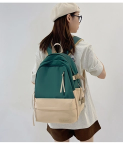Détail d'un grand sac à dos bicolore avec sangles réglables et écusson de la marque