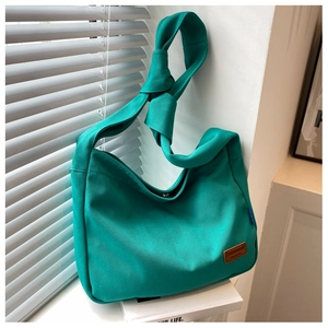 Detail of green canvas tote bag showing knotted strap, leather patch, and fabric texture