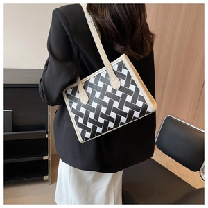 Detail of woven geometric tote bag with cream leather straps on a female model shoulder