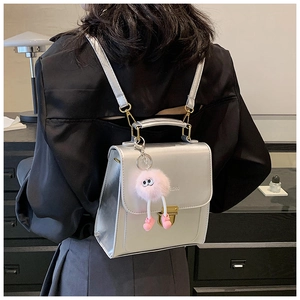 Silberner Metall-Rucksack mit Goldverschluss und Plüsch-Anhänger in modernem Ambiente