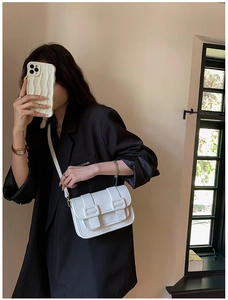 Close-up of white lychee-patterned leather crossbody bag with elegant buckle details