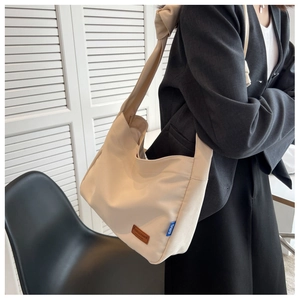 Close-up of cream canvas tote bag with unique knot detail and leather logo on shoulder strap