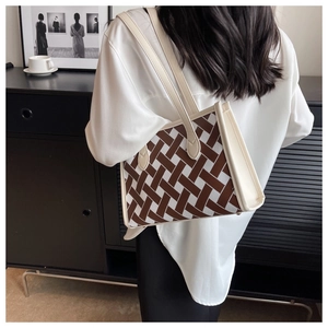 Detailed view of large brown and beige geometric tote bag worn by a model in a cafe