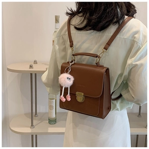 Detailansicht des braunen Vintage-PU-Lederrucksacks mit Goldschnalle und Plüsch-Anhänger