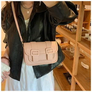 Close-up of nude pink leather crossbody bag showing pebbled texture and buckle details