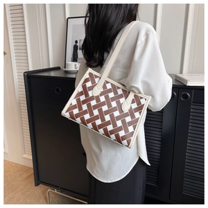 Detail of geometric woven tote bag with contrast cream leather straps and reinforced handles