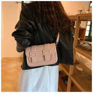 Detailed view of pink crossbody bag with pebbled leather texture and gold hardware