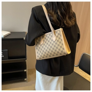 Detailed view of checkered tote bag with X patterns and beige faux leather straps