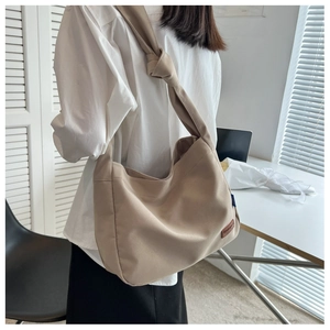 Detail of khaki canvas tote bag featuring wide shoulder strap and knotted design accent